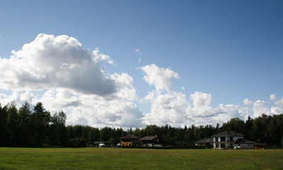 view on house and forest and sky with clouds in sunny summer day