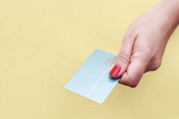 Girl holding credit card in her hand on yellow background