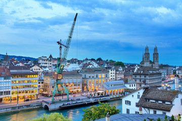 Beautiful summer cityscape panorama of the skyline of Zurich, Switzerland, with the crane at the river Limmat during the blue hour at sunset
