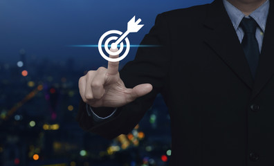 Businessman pressing target with dart flat icon over blur colorful night light city tower and...