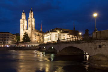 Fototapeta na wymiar Beautiful cityscape of Zurich, Switzerland, with the Grossmünster Protestant church and the Helmhaus museum, seen from the shore of the river Limmat in the blue hour in summer 
