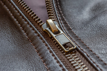 Oblique close up of the zip of an elegant brown leather jacket