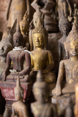 Obraz premium Close-up of many old and faded, golden and wooden Buddha statues inside the Tham Ting Cave at the famous Pak Ou Caves near Luang Prabang in Laos.