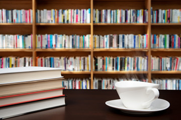books stacked on the desk with a cup of coffee.
