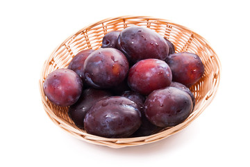 Yellow wooden basket with ripe plums isolated on a white background..