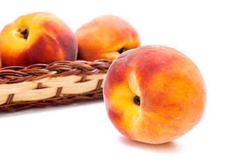 Single ripe peach fruit and several in basket isolated on white background.