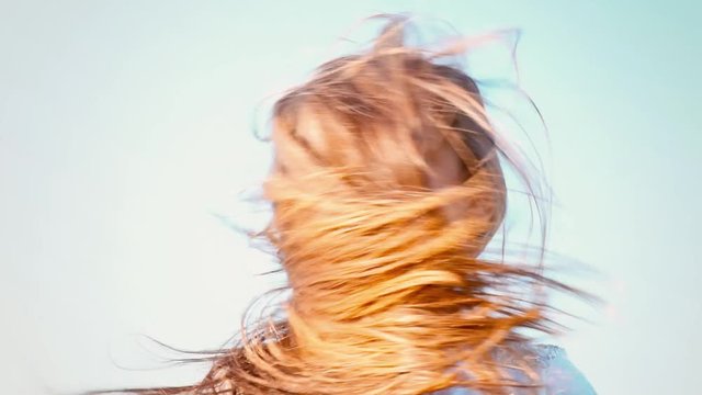 An attractive little girl with long flowing hair twists her head in different directions, girl playing with her hair in the wind, the wind develops long hair of the child