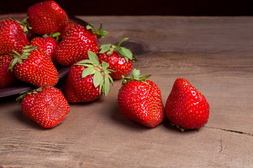 Strawberry fresh ripe sweet berry in clay plate on wooden background.