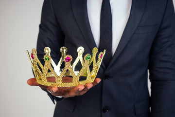 Confident businessman business king in a black classic suit with a tie and glasses put on a crown...