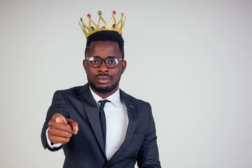 Confident businessman business king in a black classic suit with a tie and glasses put on a crown...