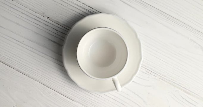 From above view of white empty cup with saucer laid on wooden background