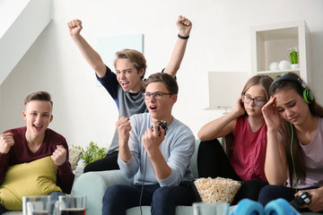 Teenagers playing video games at home