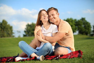 Young couple resting in park on sunny day