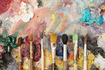 Paintbrushes closeup, artist palette and multicolor paint stains