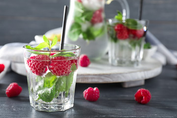 Glass of fresh raspberry mojito on wooden table