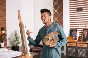 Young African-American artist painting picture at home