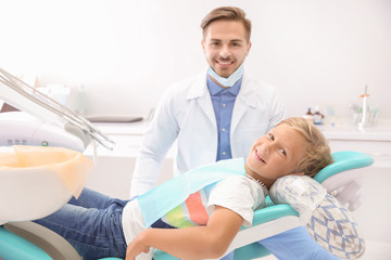 Fototapeta premium Dentist examining little boy's teeth in clinic