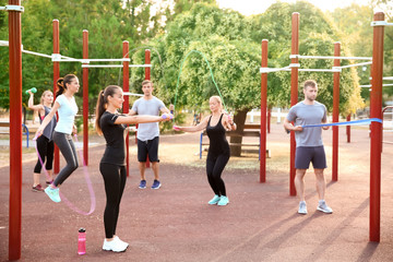 Group of sporty people training on athletic field outdoors