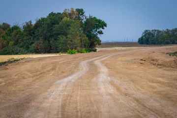 Fototapeta na wymiar Rural not asphalted road passing through an agricultural field.