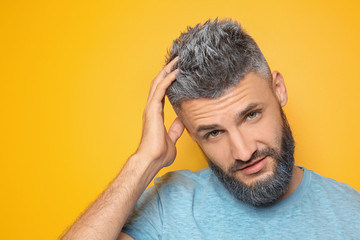 Portrait of handsome man with dyed hair and beard on color background