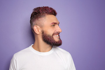 Fototapeta premium Portrait of handsome man with dyed hair and beard on color background