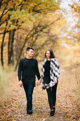 Fototapeta premium A loving couple walking in the forest. Autumn mood and colors around