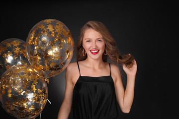 Naklejka premium Beautiful young woman with balloons on dark background