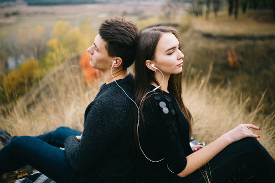 Loving couple listens music together outdoor in autumn