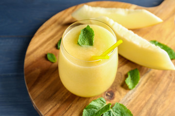 Glass of fresh melon smoothie on wooden board