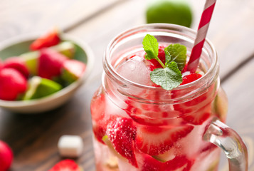 Mason jar of fresh strawberry mojito on table, closeup