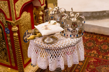 Two crowns before the wedding ceremony in church. Close-up photo of two golden rings on the table in the church.