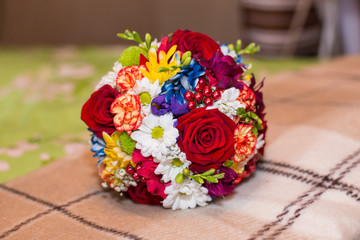 Autumn hued fresh floral wedding bouquet with dashing red pink and orange roses using yellow and brown wildflowers for added neutral seasonal affect.