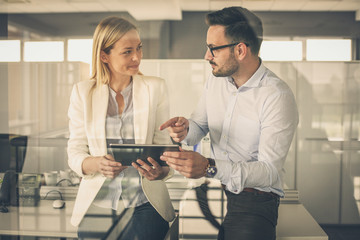  Business woman showing something to her colleague on digital tablet.