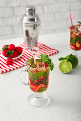 Glass of fresh strawberry mojito on white table