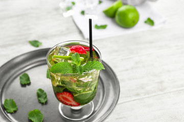 Glass of fresh strawberry mojito on white wooden table