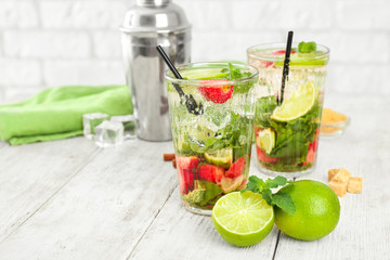 Glasses of fresh strawberry mojito on white wooden table