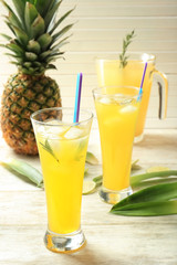 Tasty fresh cocktails with pineapple in glass on light wooden background