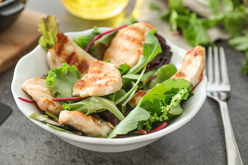 Plate with tasty chicken salad on grey table