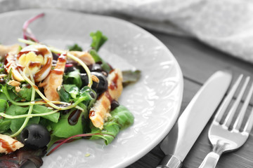 Plate with tasty chicken salad on wooden table