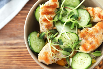Bowl with tasty chicken salad on wooden table