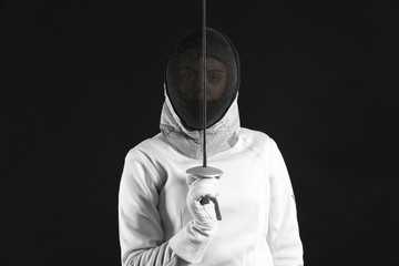 Young female fencer on dark background