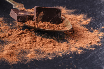 Cocoa powder and chocolate in spoon on slate