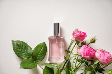 Bottle of perfume with beautiful flowers on white background