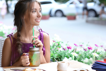 Young woman drinking fresh lemonade in cafe