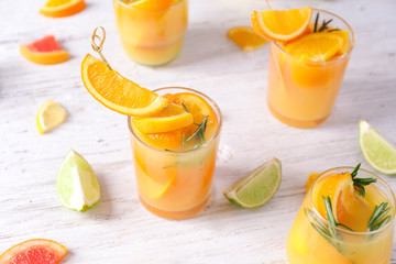 Glasses of tasty cocktails and fruits on white wooden table