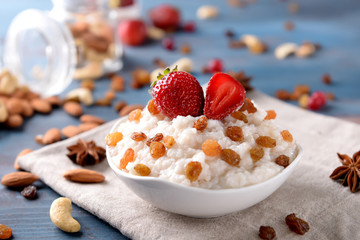 Bowl with delicious rice pudding, raisins and strawberry on napkin