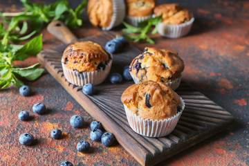 Tasty blueberry muffins on wooden board