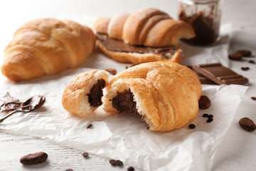 Tasty croissant with chocolate on white table