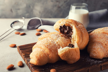 Tasty croissants with chocolate on wooden board