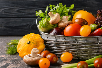 Basket with various fresh vegetables on dark table